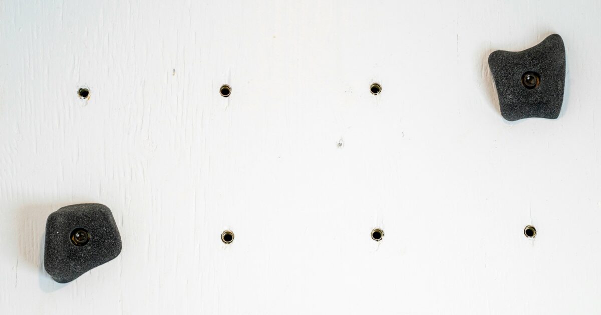 白い壁に取り付けられた黒いクライミングホールド