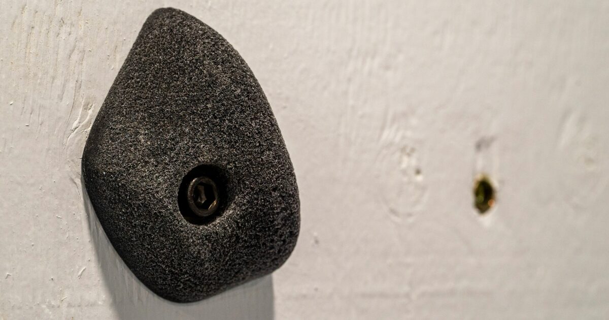 白い壁に取り付けられた黒いクライミングホールドのクローズアップ