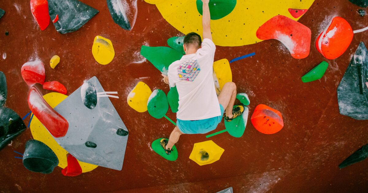 カラフルなホールドを使ってダイナミックに登る男性クライマー