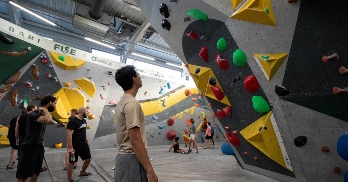 室内ボルダリングジムで課題を見上げるクライマーたち