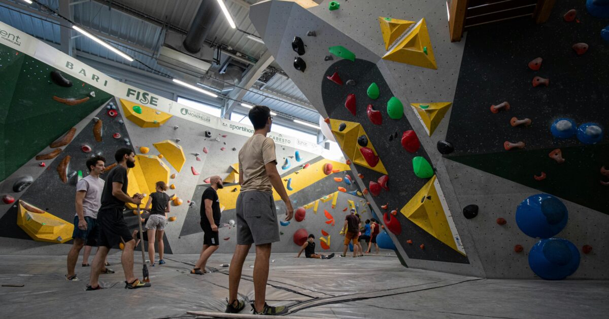 クライマーたちが挑戦する大型のボルダリングウォールとカラフルなホールド