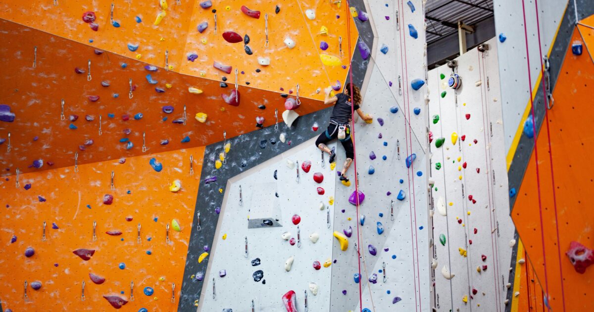 屋内リードクライミングジムで登る女性クライマー