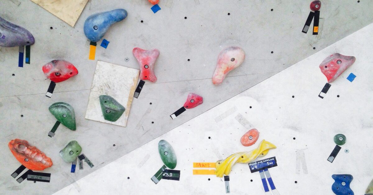 白いクライミングウォールに設置されたカラフルなホールドのクローズアップ