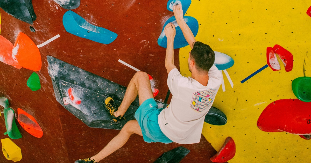 カラフルなホールドを使って壁を登る男性クライマー