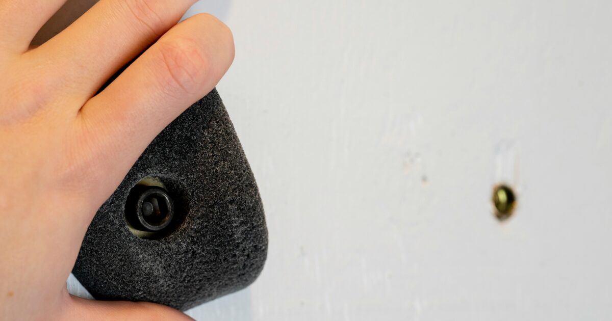 黒いクライミングホールドを掴む手のアップ