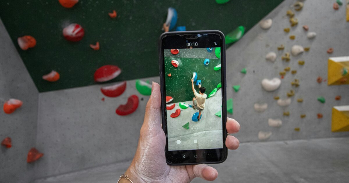 スマートフォン越しにボルダリングを撮影する様子